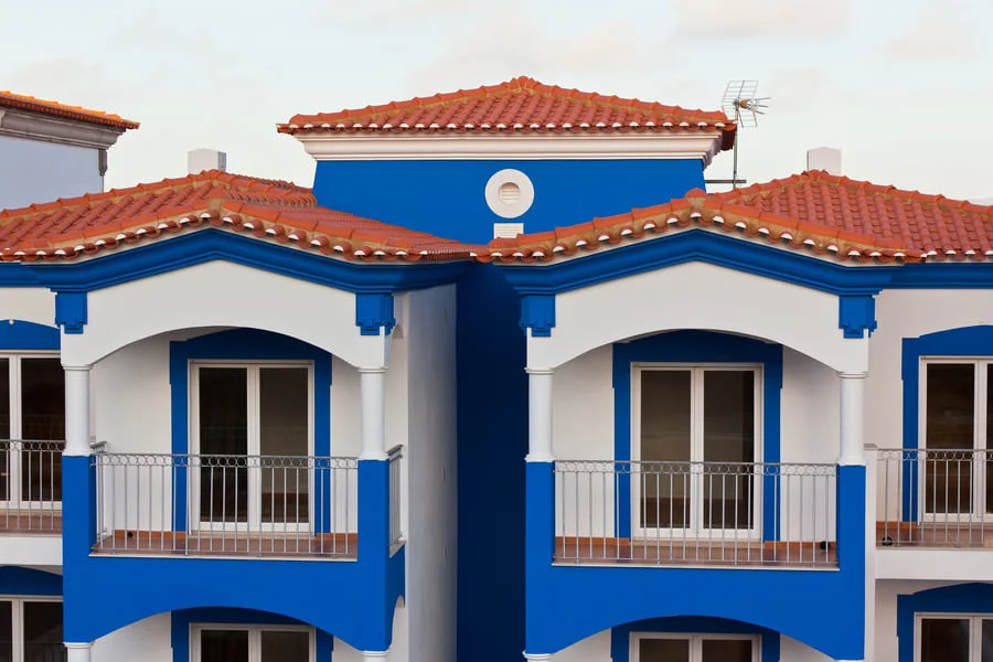 Mediterranean-style blue and white house with red roof tiles.