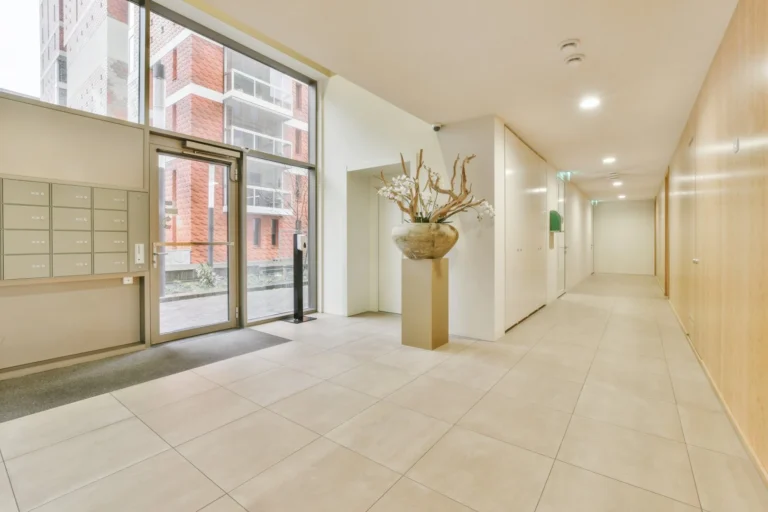 Modern apartment hall with large windows and decorative vase.