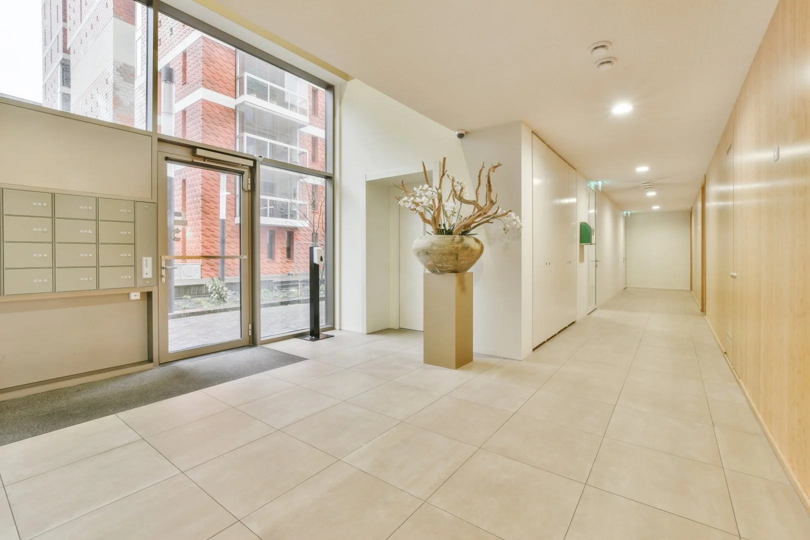 Modern apartment hall with large windows and decorative vase.